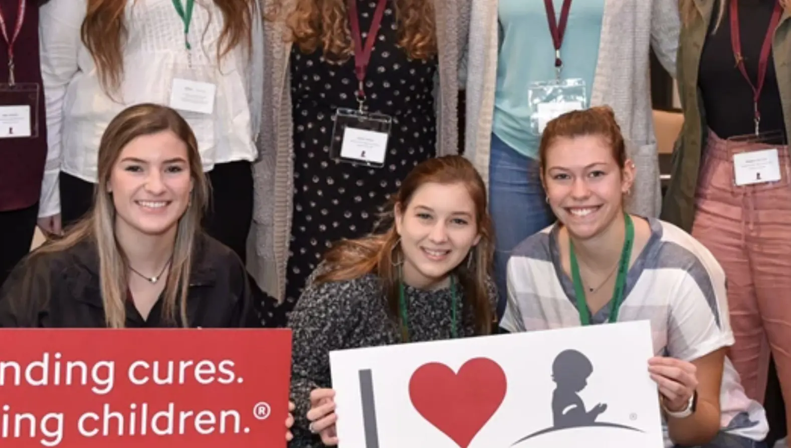 Students smiling holding Saint Jude signs