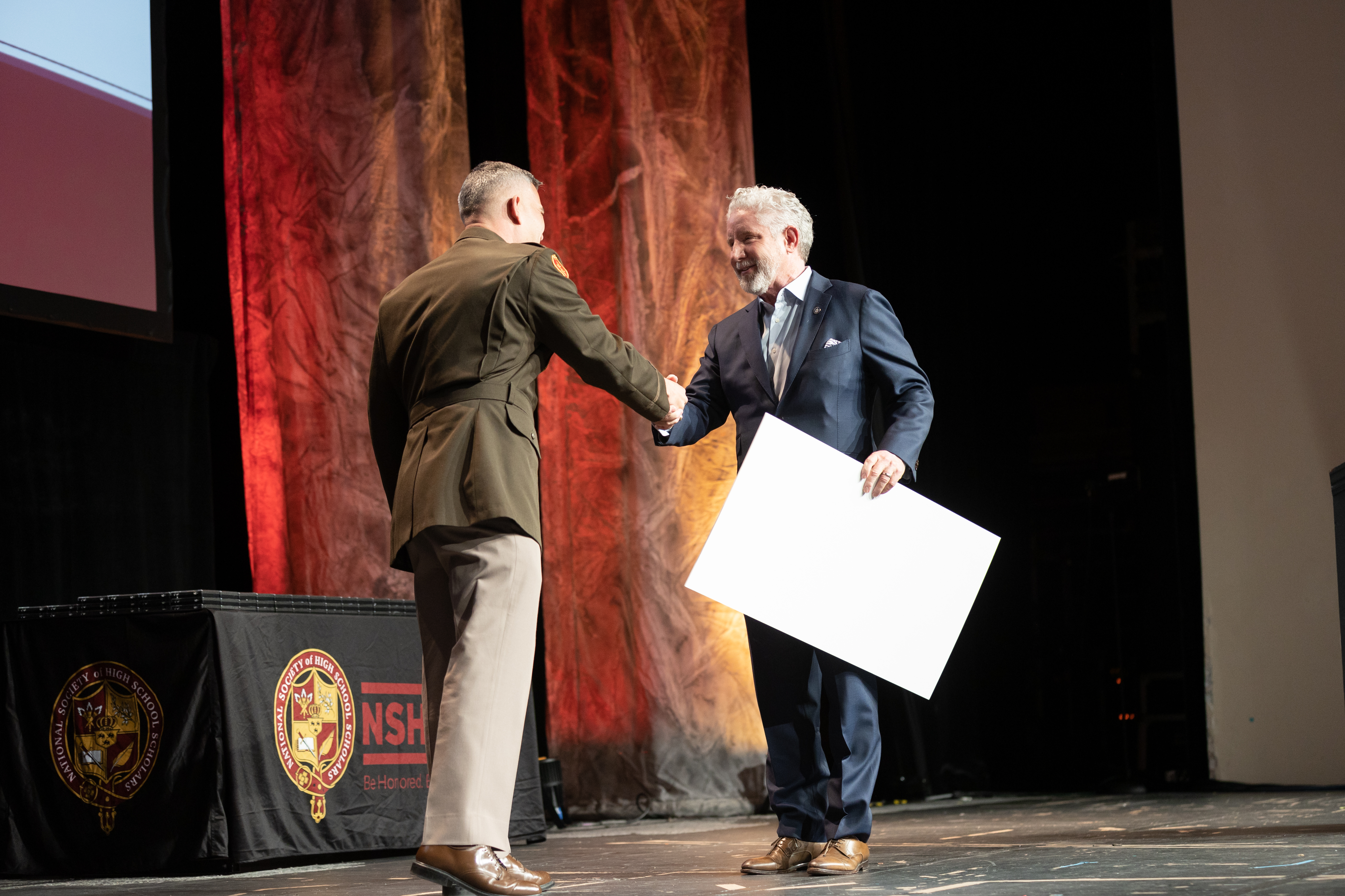 A man shaking another man's hand on stage