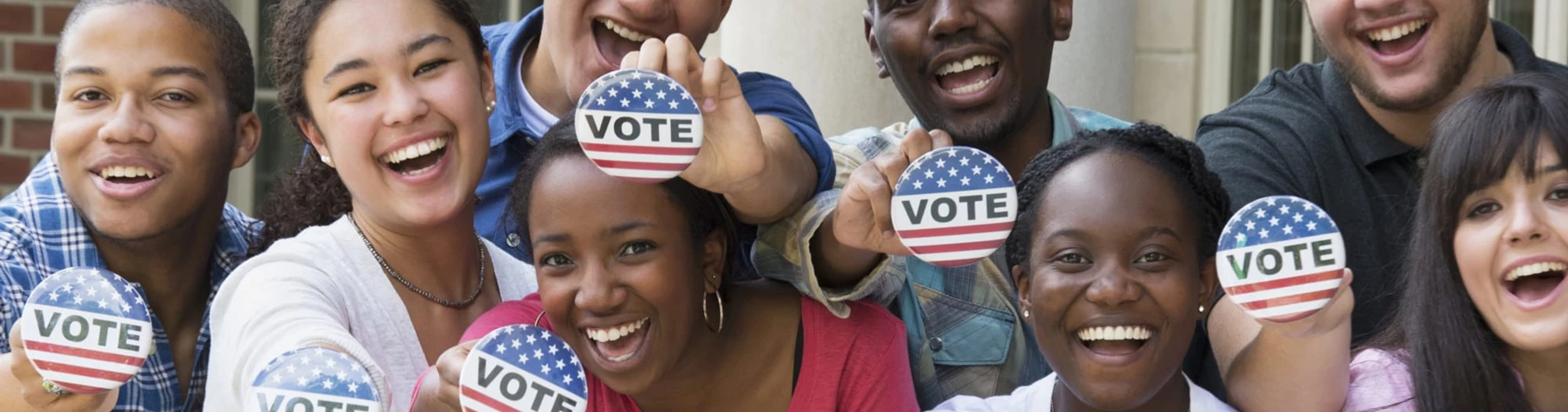 A diverse group of people raising vote stickers